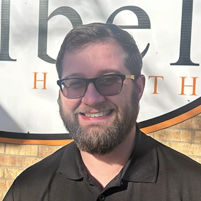 Chiropractor Rees Kopecky Smiling In Front Of Brick Wall